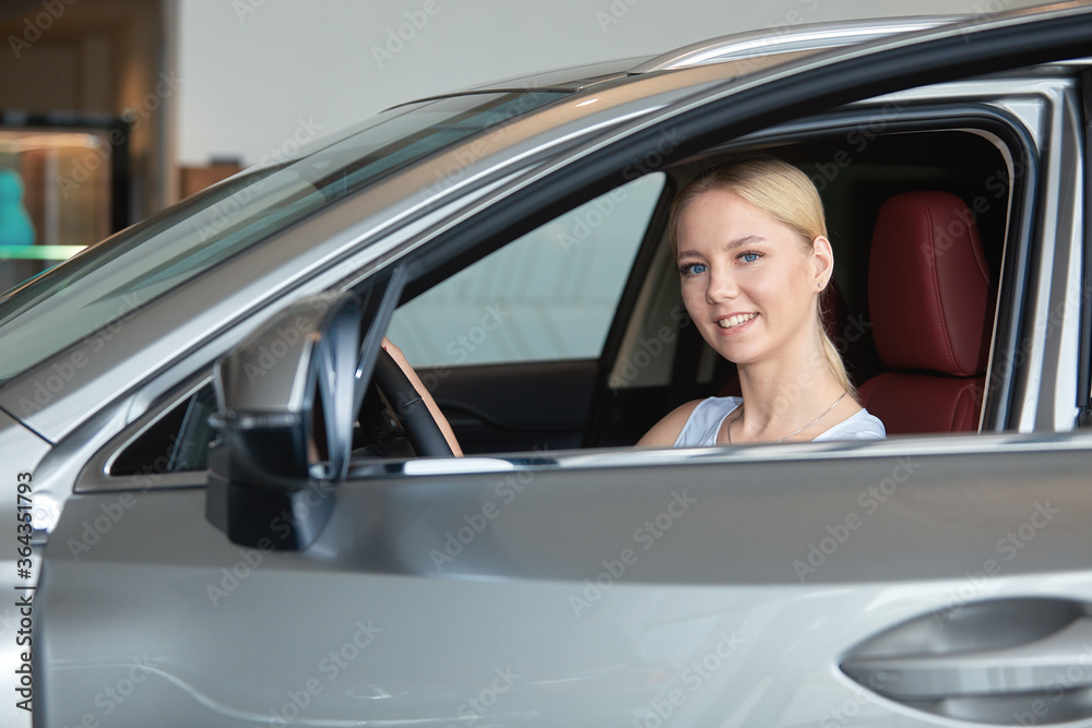 Portrait of a happy young girl buying a new car at a dealership