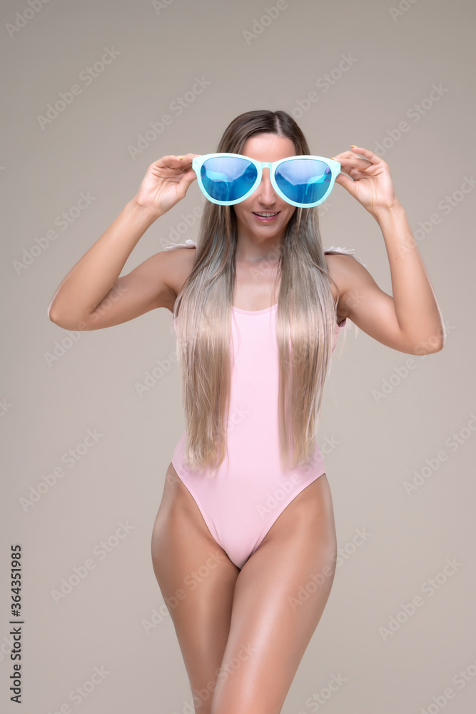 Beautiful slim and fit girl with long blond hair in pink swimsuit. Glowing skin Beautiful slim and fit girl with long blond hair in pink swimsuit. Glowing skin