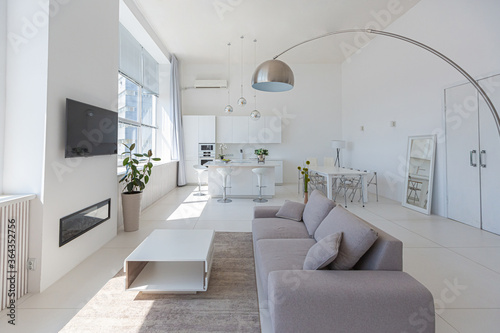Cozy luxury modern interior design of a studio apartment in extra white colors with fashionable expensive furniture in a minimalist style. white tiled floor  kitchen  relaxation area and workplace