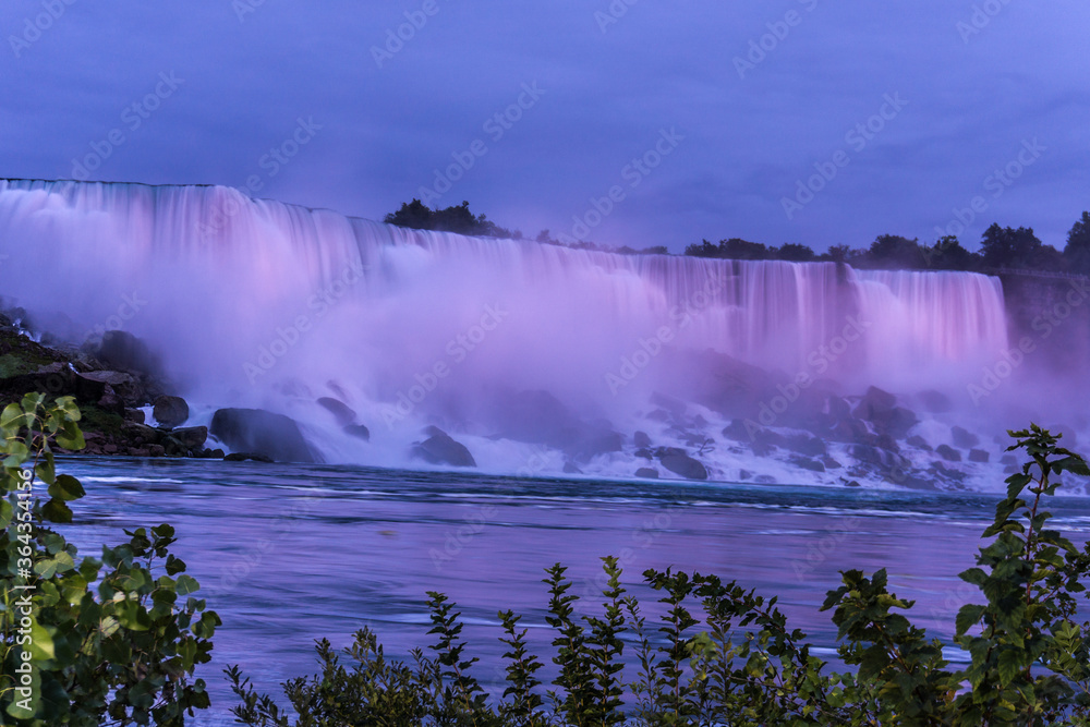 Thunderous Niagara waterfalls in night with colorful lights in Niagara, Ontario, Canada