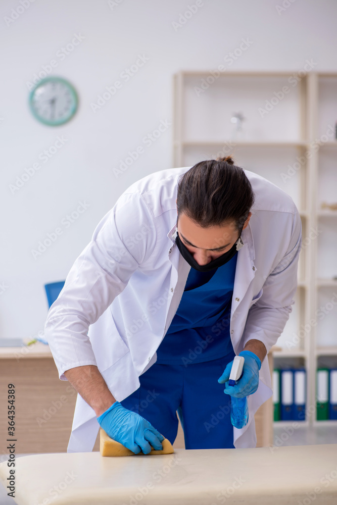 Young male contractor disinfecting clinic in pandemic concept