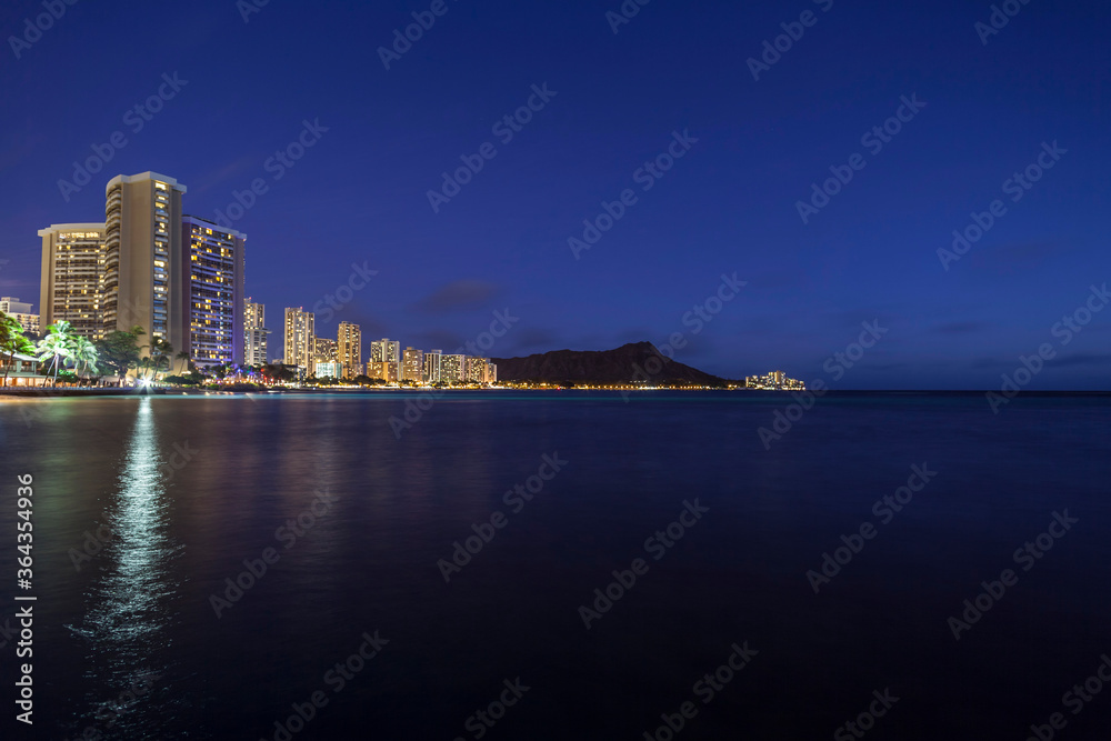 Waikiki Beach Honolulu Hawaii resort hotels and diamond head peak at night.
