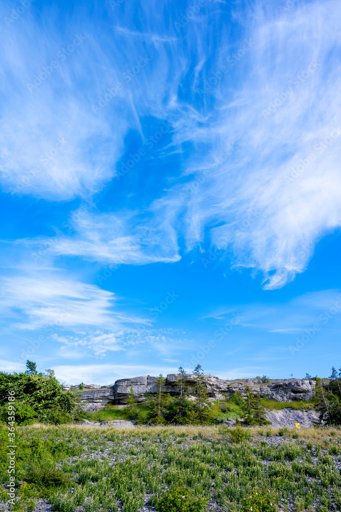 Limestone cliff face under blue cloudy sky Limestone cliff face under blue cloudy sky