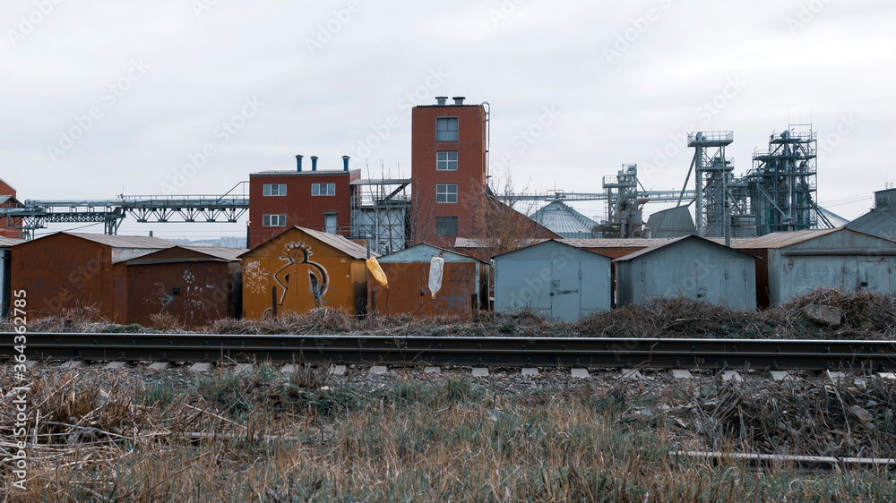 Railway tracks on the background of garages and a factory in the Russian province.