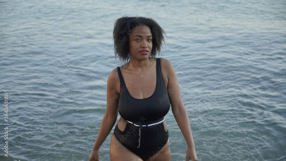 young african american woman walking in the sea.Young woman walks into the cold water on the beach young african american woman walking in the sea.Young woman walks into the cold water on the beach