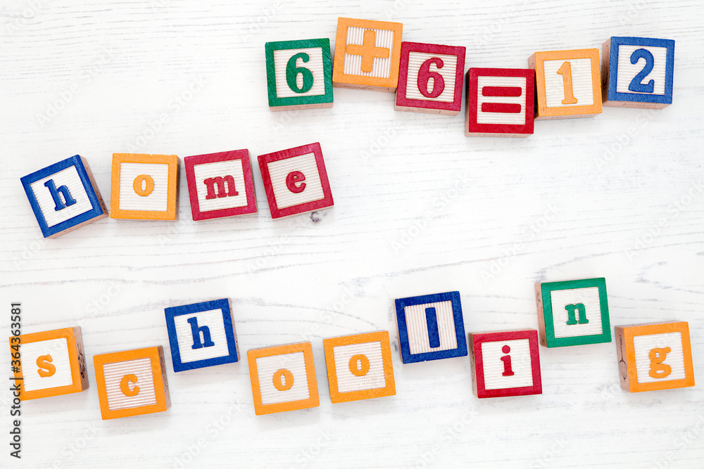 Children’s wooden spelling blocks spell out the words home schooling and a simple sum. Children’s wooden spelling blocks spell out the words home schooling and a simple sum.