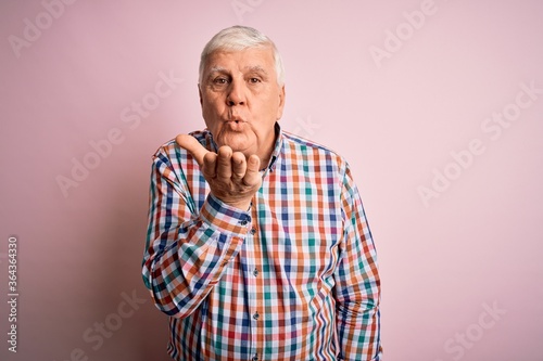 Senior handsome hoary man wearing casual colorful shirt over isolated pink background looking at the camera blowing a kiss with hand on air being lovely and sexy. Love expression.