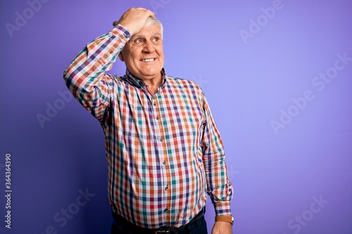 Senior handsome hoary man wearing casual colorful shirt over isolated purple background smiling confident touching hair with hand up gesture, posing attractive and fashionable