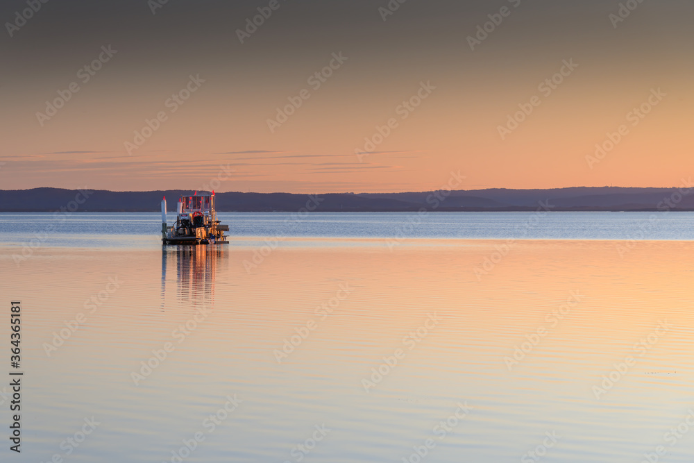 Soft Sunset over the Lake with Clear Skies and a harvester
