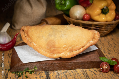 Fresh fogazza on top of wood with blurred background decorated with vegetables, wooden roll and flour photo