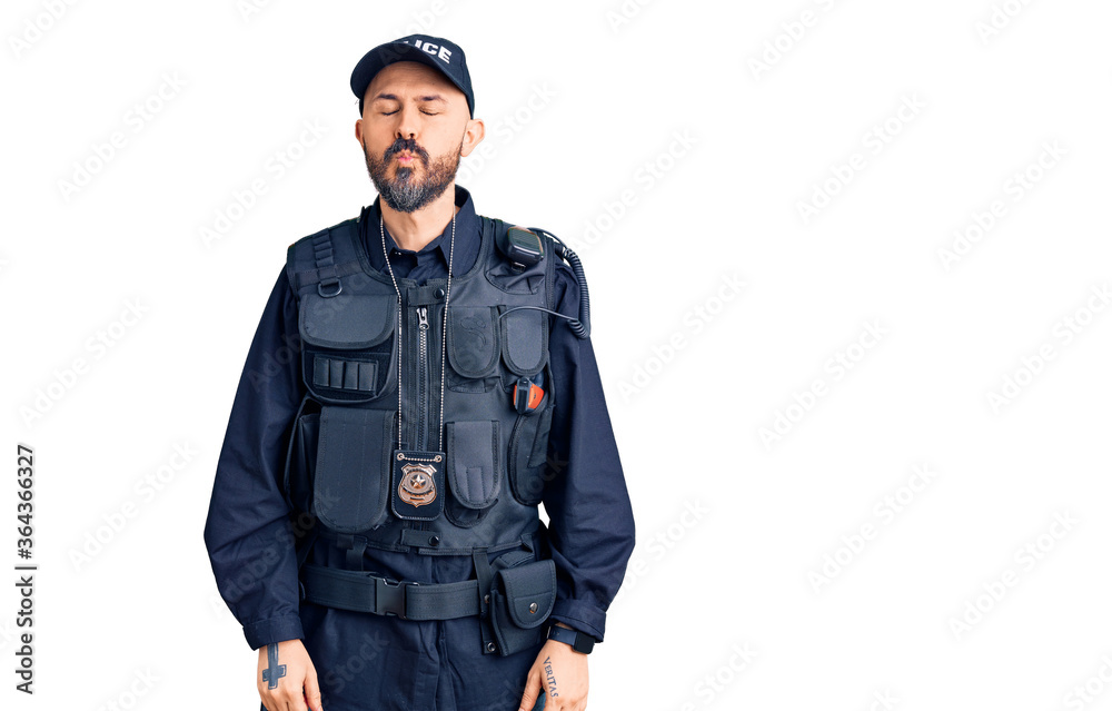 Young handsome man wearing police uniform looking at the camera blowing a kiss on air being lovely and sexy. love expression. Young handsome man wearing police uniform looking at the camera blowing a kiss on air being lovely and sexy. love expression.