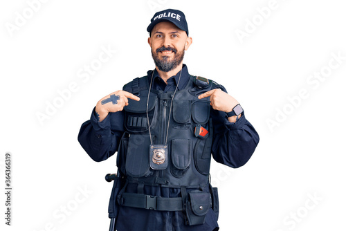 Young handsome man wearing police uniform looking confident with smile on face, pointing oneself with fingers proud and happy.