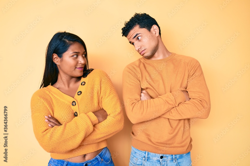 Beautiful latin young couple wearing casual clothes together looking to the side with arms crossed convinced and confident Beautiful latin young couple wearing casual clothes together looking to the side with arms crossed convinced and confident