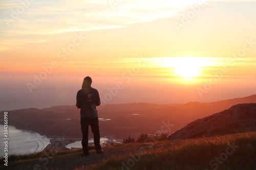 silhouette of a man watching sunset over ocean