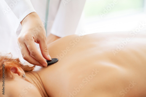 Spa stone massage, beautiful woman getting spa hot stones massage in spa salon.