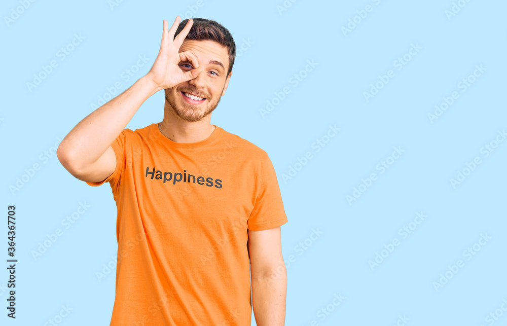 Handsome young man with bear wearing tshirt with happiness word message doing ok gesture with hand smiling, eye looking through fingers with happy face. Handsome young man with bear wearing tshirt with happiness word message doing ok gesture with hand smiling, eye looking through fingers with happy face.