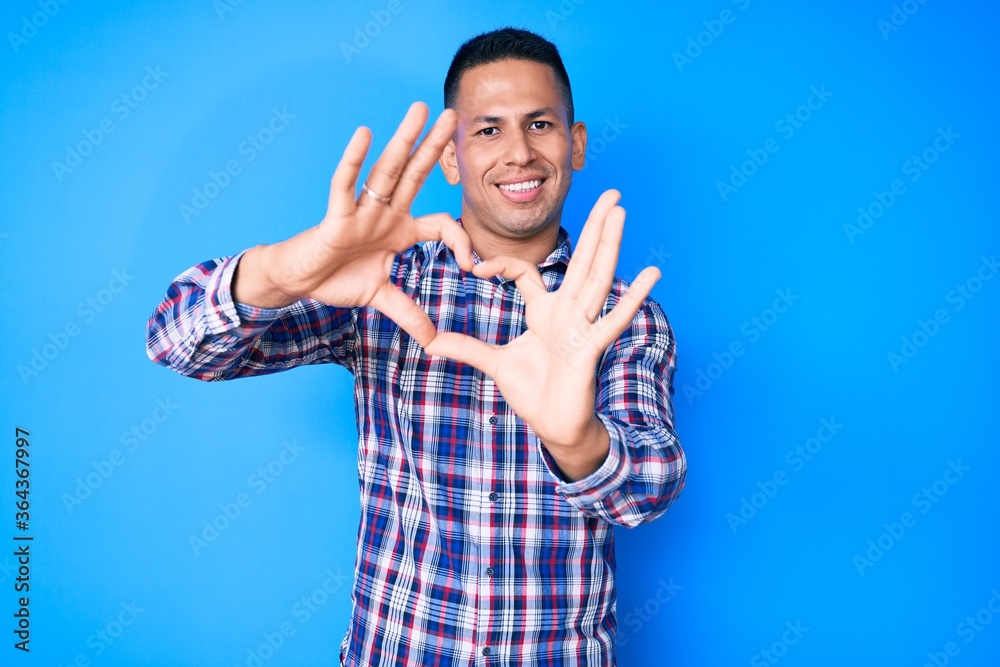Fototapeta premium Young handsome latin man wearing casual clothes smiling in love doing heart symbol shape with hands. romantic concept.