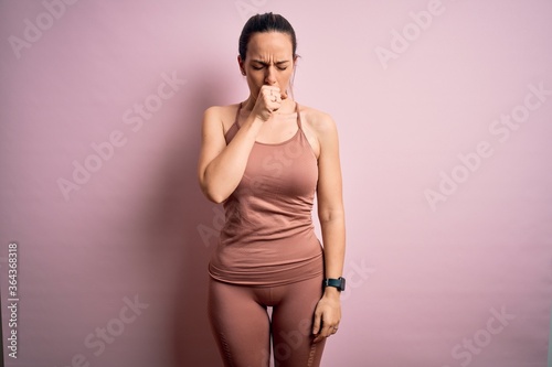 Young blonde fitness woman wearing sport workout clothes over pink isolated background feeling unwell and coughing as symptom for cold or bronchitis. Health care concept.