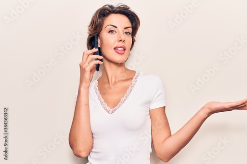 Young beautiful woman having conversation talking on the smartphone celebrating achievement with happy smile and winner expression with raised hand