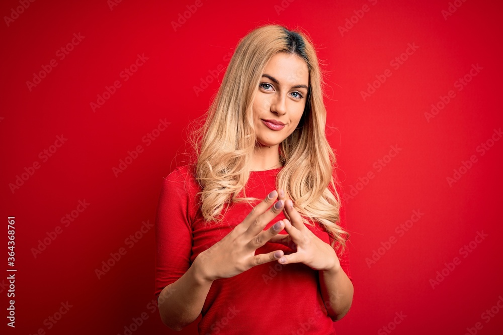 Young beautiful blonde woman wearing casual t-shirt standing over isolated red background Hands together and fingers crossed smiling relaxed and cheerful. Success and optimistic Young beautiful blonde woman wearing casual t-shirt standing over isolated red background Hands together and fingers crossed smiling relaxed and cheerful. Success and optimistic