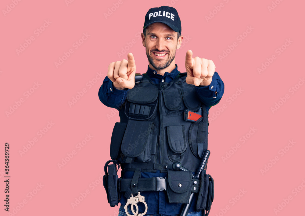 Young handsome man wearing police uniform pointing to you and the camera with fingers, smiling positive and cheerful Young handsome man wearing police uniform pointing to you and the camera with fingers, smiling positive and cheerful