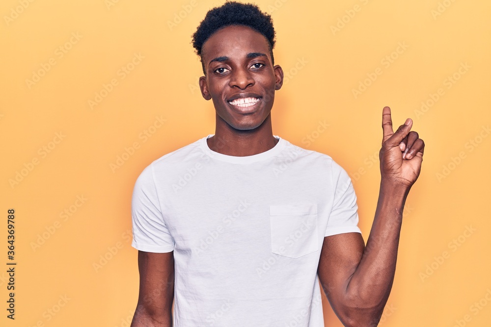 Young african american man wearing casual clothes with a big smile on face, pointing with hand finger to the side looking at the camera. Young african american man wearing casual clothes with a big smile on face, pointing with hand finger to the side looking at the camera.