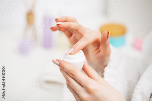 Close up of woman holding moisturizer for facial skin care