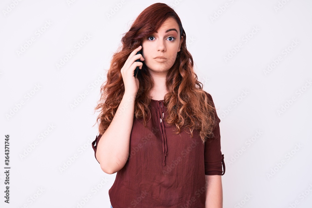 Young beautiful woman having conversation talking on the smartphone thinking attitude and sober expression looking self confident Young beautiful woman having conversation talking on the smartphone thinking attitude and sober expression looking self confident