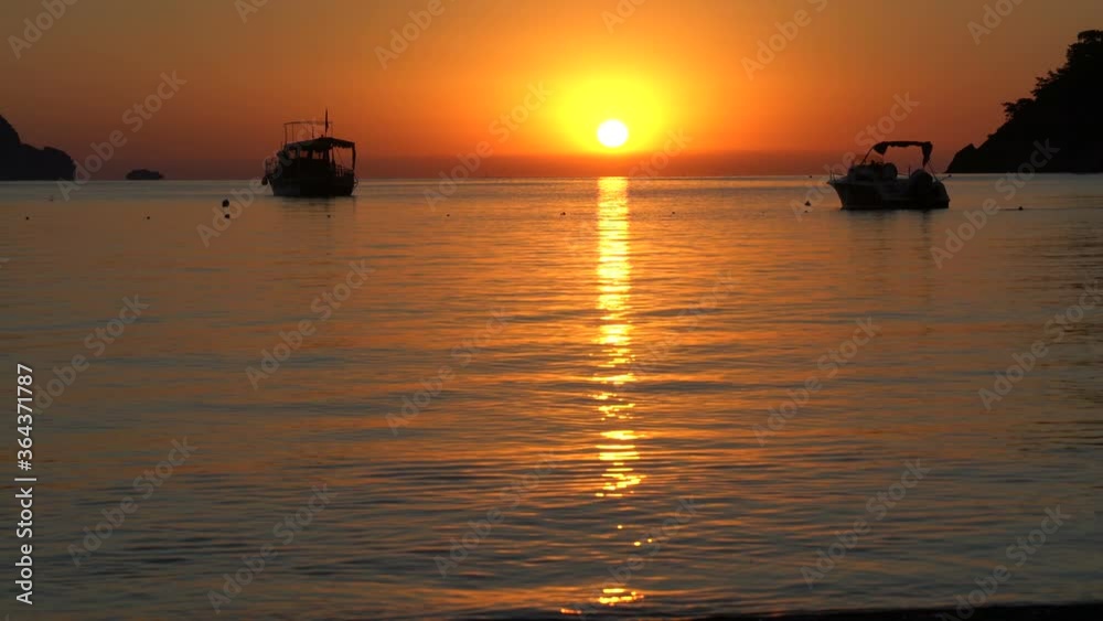 Beautiful sunrise on the sea. Adrasan village on the long beach and Mediterranean coast, sea and mountains in the background, silhouette boats, a great place for vacation. Antalya Turkey Beautiful sunrise on the sea. Adrasan village on the long beach and Mediterranean coast, sea and mountains in the background, silhouette boats, a great place for vacation. Antalya Turkey