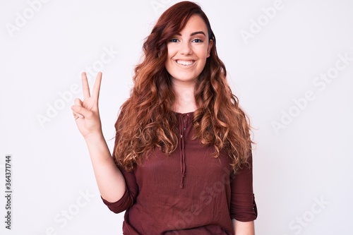 Young beautiful woman wearing casual clothes smiling with happy face winking at the camera doing victory sign. number two.