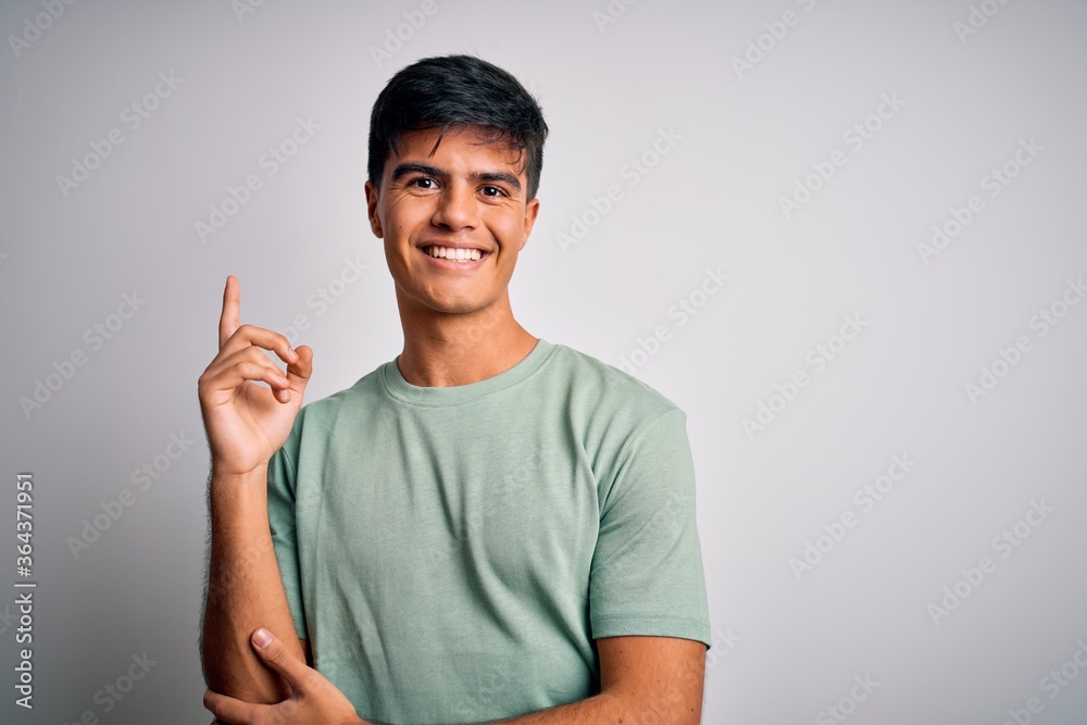 Young handsome man wearing casual t-shirt standing over isolated white background with a big smile on face, pointing with hand and finger to the side looking at the camera. Young handsome man wearing casual t-shirt standing over isolated white background with a big smile on face, pointing with hand and finger to the side looking at the camera.
