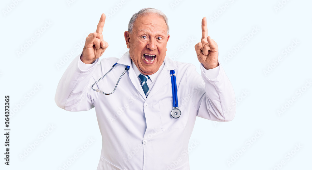 Senior handsome grey-haired man wearing doctor coat and stethoscope shouting with crazy expression doing rock symbol with hands up. music star. heavy music concept. Senior handsome grey-haired man wearing doctor coat and stethoscope shouting with crazy expression doing rock symbol with hands up. music star. heavy music concept.