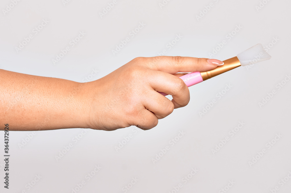Hand of caucasian young woman holding eye brush over isolated white background Hand of caucasian young woman holding eye brush over isolated white background
