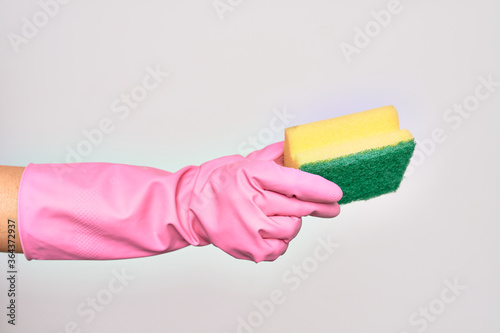 Hand of caucasian young woman wearing cleaning glove holding scourer sponge over isolated white background