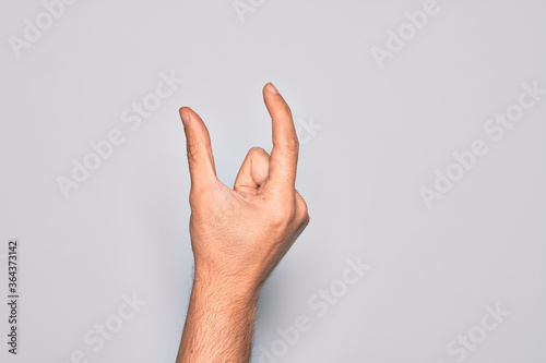 Hand of caucasian young man showing fingers over isolated white background picking and taking invisible thing, holding object with fingers showing space