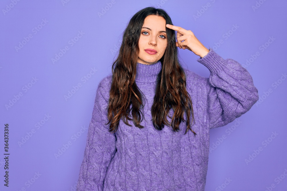 Young beautiful woman wearing casual turtleneck sweater standing over purple background pointing unhappy to pimple on forehead, ugly infection of blackhead. Acne and skin problem Young beautiful woman wearing casual turtleneck sweater standing over purple background pointing unhappy to pimple on forehead, ugly infection of blackhead. Acne and skin problem