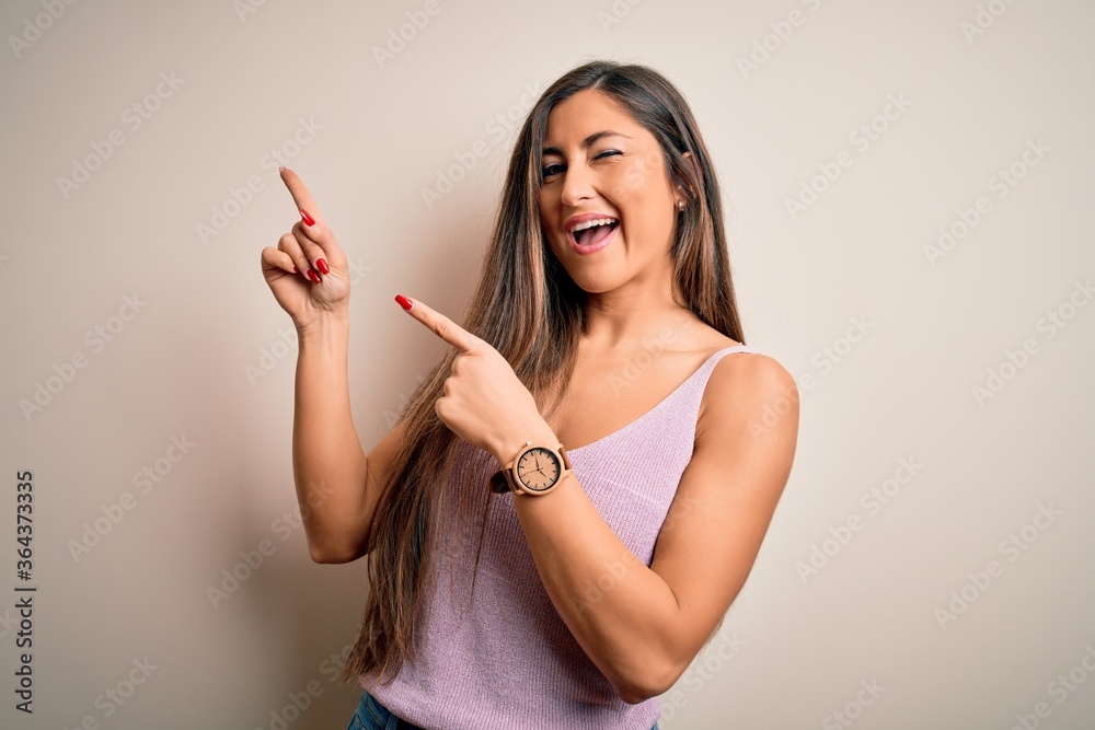 Young beautiful brunette woman with long hair standing over isolated background smiling and looking at the camera pointing with two hands and fingers to the side. Young beautiful brunette woman with long hair standing over isolated background smiling and looking at the camera pointing with two hands and fingers to the side.