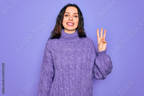 Young beautiful woman wearing casual turtleneck sweater standing over purple background showing and pointing up with fingers number three while smiling confident and happy.
