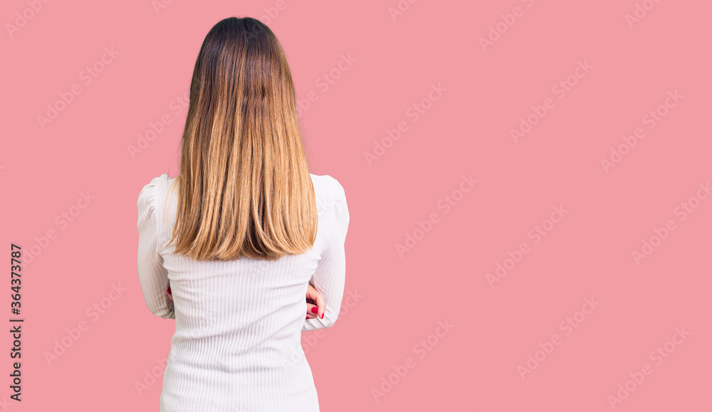 Beautiful brunette young woman wearing casual white sweater and glasses standing backwards looking away with crossed arms Beautiful brunette young woman wearing casual white sweater and glasses standing backwards looking away with crossed arms