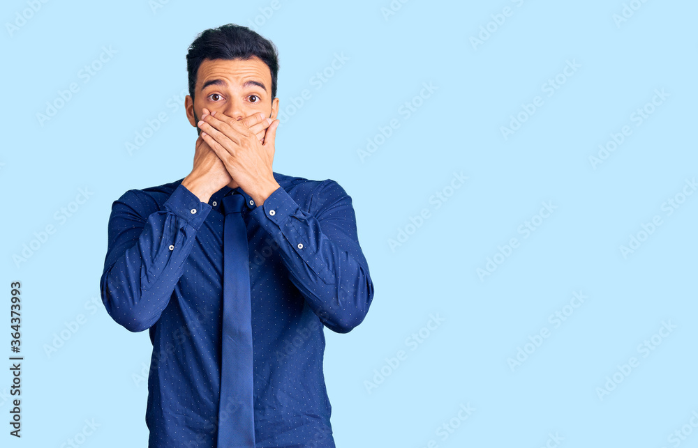 Young handsome hispanic man wearing business clothes shocked covering mouth with hands for mistake. secret concept. Young handsome hispanic man wearing business clothes shocked covering mouth with hands for mistake. secret concept.