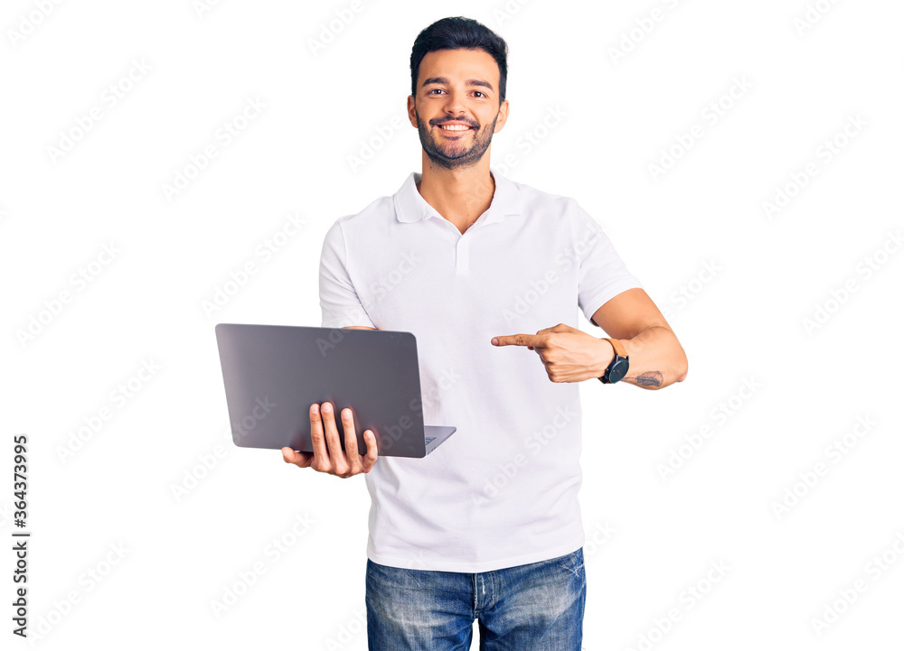 Young handsome hispanic man working using computer laptop smiling happy pointing with hand and finger Young handsome hispanic man working using computer laptop smiling happy pointing with hand and finger