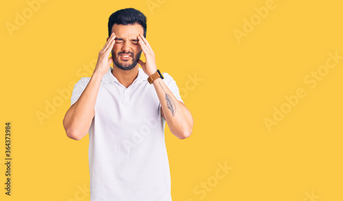 Young handsome hispanic man wearing casual clothes with hand on head, headache because stress. suffering migraine. © Krakenimages.com