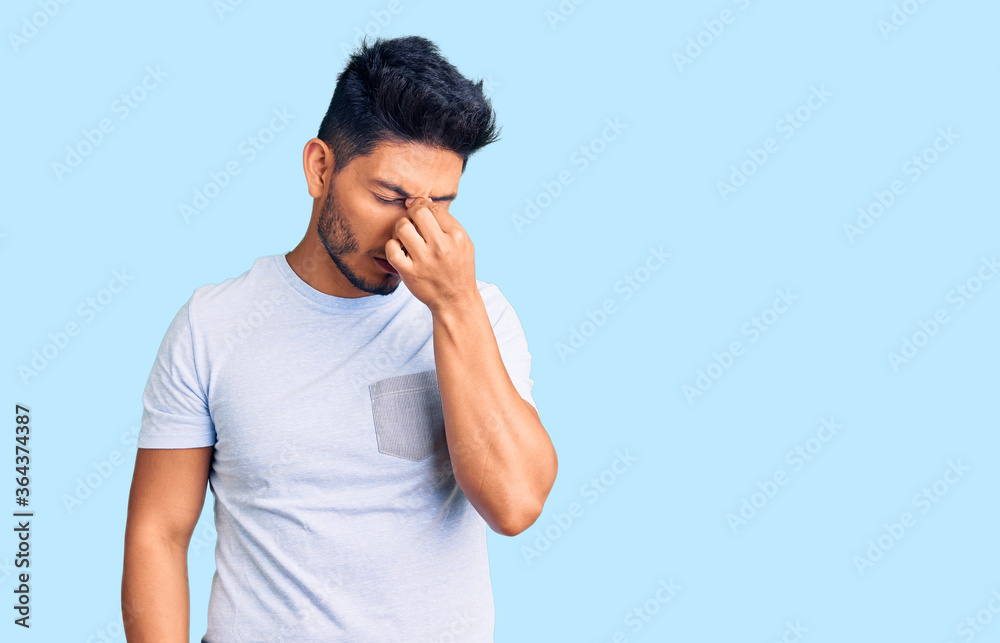 Handsome latin american young man wearing casual clothes tired rubbing nose and eyes feeling fatigue and headache. stress and frustration concept. Handsome latin american young man wearing casual clothes tired rubbing nose and eyes feeling fatigue and headache. stress and frustration concept.