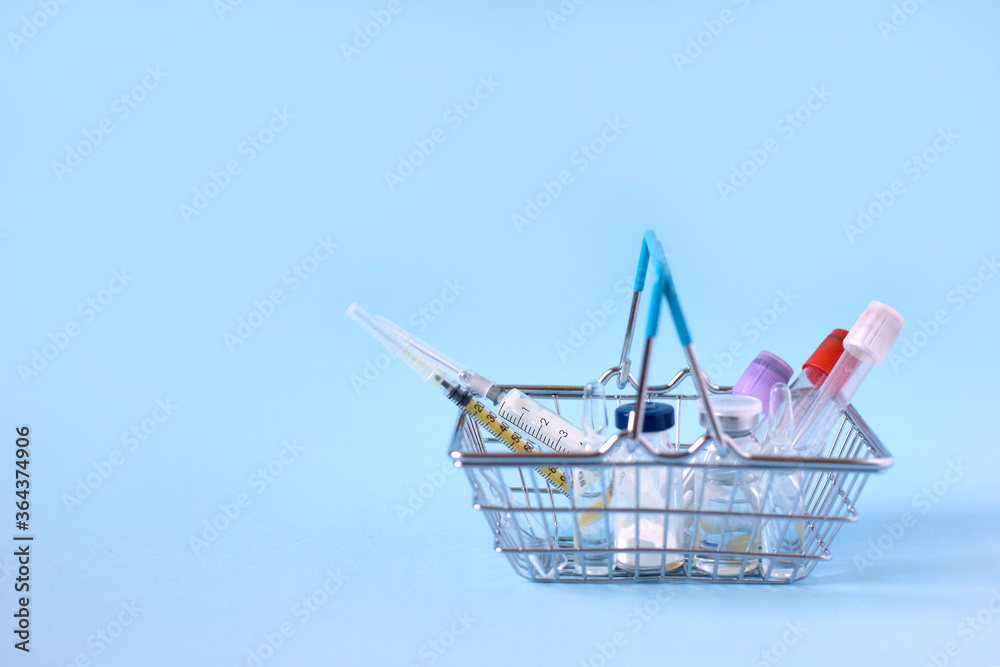 Shopping basket with syringes, injections, vaccines and blood tubes on a blue background. Covid 19 vaccination Shopping basket with syringes, injections, vaccines and blood tubes on a blue background. Covid 19 vaccination