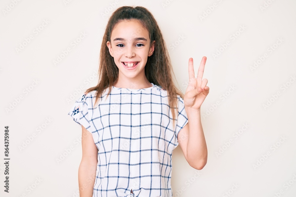 Cute hispanic child girl wearing casual clothes smiling with happy face winking at the camera doing victory sign. number two. Cute hispanic child girl wearing casual clothes smiling with happy face winking at the camera doing victory sign. number two.
