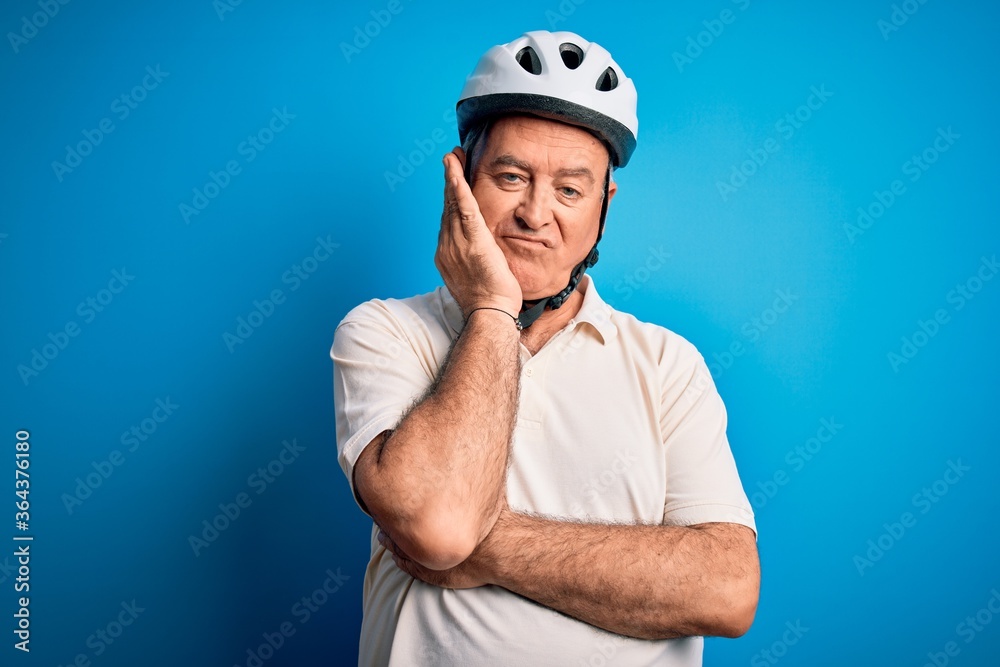 Middle age hoary cyclist man wearing bike security helmet over isolated blue background thinking looking tired and bored with depression problems with crossed arms. Middle age hoary cyclist man wearing bike security helmet over isolated blue background thinking looking tired and bored with depression problems with crossed arms.