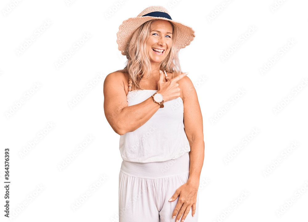 Middle age fit blonde woman wearing summer hat cheerful with a smile of face pointing with hand and finger up to the side with happy and natural expression on face Middle age fit blonde woman wearing summer hat cheerful with a smile of face pointing with hand and finger up to the side with happy and natural expression on face