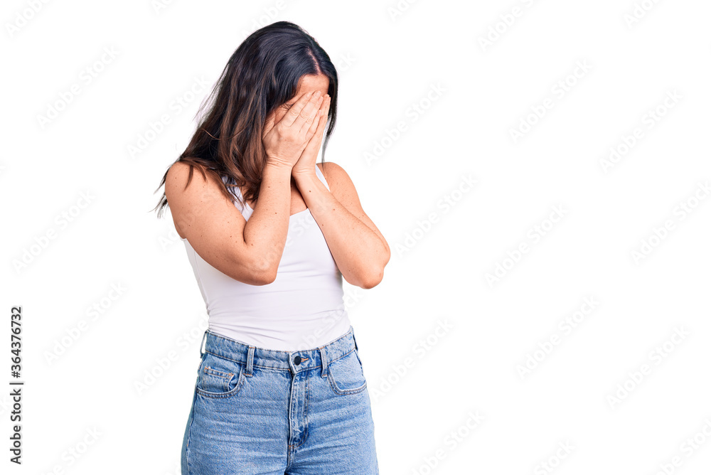 Young beautiful brunette woman wearing casual sleeveless t-shirt with sad expression covering face with hands while crying. depression concept. Young beautiful brunette woman wearing casual sleeveless t-shirt with sad expression covering face with hands while crying. depression concept.