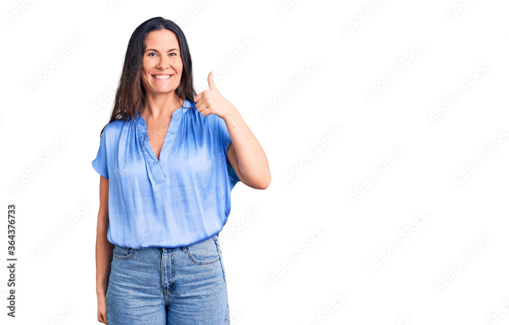 Young beautiful brunette woman wearing casual t-shirt smiling happy and positive, thumb up doing excellent and approval sign Young beautiful brunette woman wearing casual t-shirt smiling happy and positive, thumb up doing excellent and approval sign