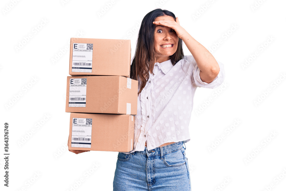 Young beautiful brunette woman holding delivery cardboard package stressed and frustrated with hand on head, surprised and angry face Young beautiful brunette woman holding delivery cardboard package stressed and frustrated with hand on head, surprised and angry face